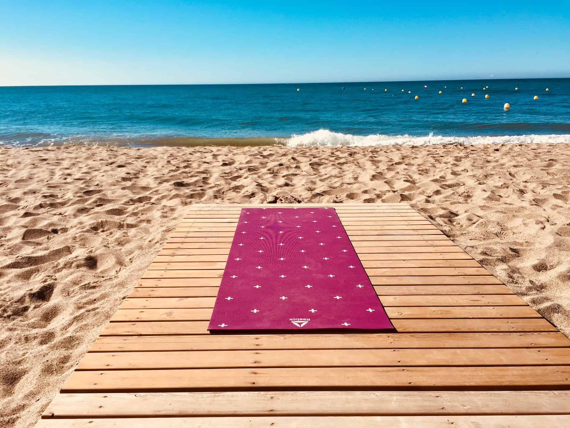 Espacio de bienestar junto al mar, esterilla sobre pasarela de madera frente a la playa
